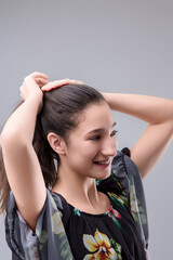 Young woman making ponytail with long hair