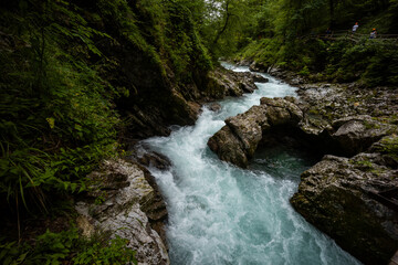Vintgar Gorges Park a few km from Lake Bled, Slovenia. Wooden walkways accompany the path above the river rapids and waterfalls. River hits rocks and creates fog.Adventure family holidays. Freshness.