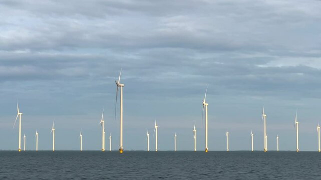 Drive by flybe moving shot of rotating fan propellor blde of offshore wind mill, windmills or turbine at seagenerating green sustainable electric energy