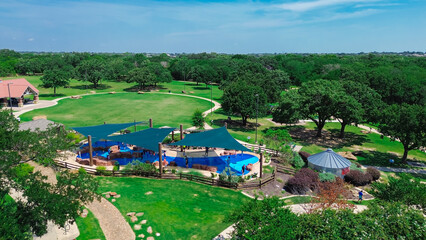 Slash pad with sail shade structure and diverse kids playing water in large modern children...