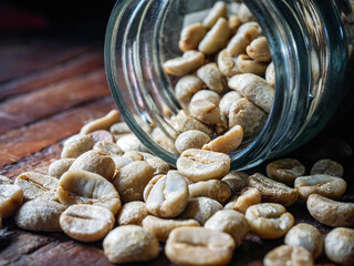 Green coffee beans poured out of a glass jar, Close-up of green raw coffee bean, unroasted coffee...