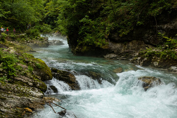 Fototapeta premium Vintgar Gorges Park a few km from Lake Bled, Slovenia. Wooden walkways accompany the path above the river rapids and waterfalls. River hits rocks and creates fog.Adventure family holidays. Freshness.
