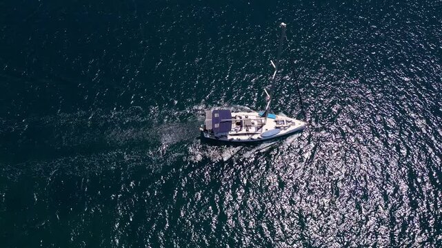 Aerial view of a sailboat cruising over deep blue and turquoise waters in Sithonia, Greece, capturing the essence of nautical adventure and the serene beauty of the sea