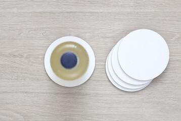 Coasters with beer bottle. White round mockups on a wooden table