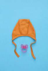 Newborn baby hat and pacifier on blue background