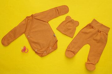 Newborn baby clothes on yellow background. Top view. Flat lay