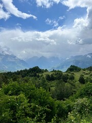 Obraz premium Verdant Hills with Rocky Mountains and Blue Sky – Ideal for Nature Enthusiasts and Landscape Photography