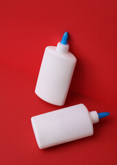 Two bottles of pva glue on red background