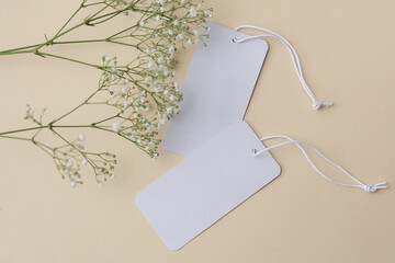 White blank price tags and gypsophila flowers on beige background