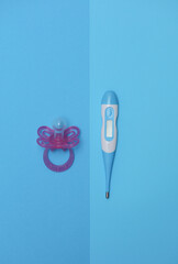 Electronic thermometer and pacifier for newborns on a blue background. Caring for baby's health