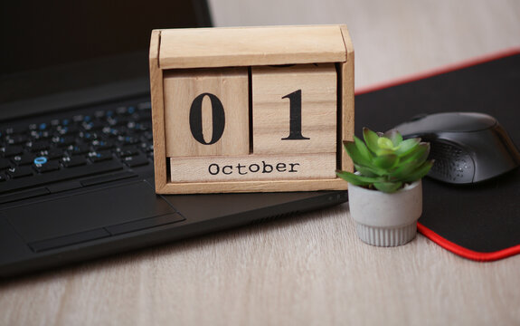 Wooden calendar with the date October 01 on a desktop with a laptop