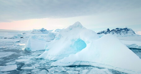 Frozen Arctic ice floes winter landscape. Icebergs floating cold polar ocean, mountains range in background. Antarctica glacier seascape close up. Ecology, climate change. Travel background panorama