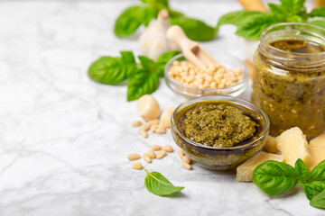 Pesto. Italian basil pesto sauce on a textured wooden background. Ingredient for pesto sauce: fresh basil, pine nuts, Parmesan cheese and olive oil. Space for text.Copy space.