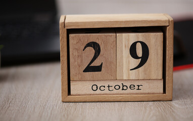 Wooden calendar with the date October 29 on desktop with laptop