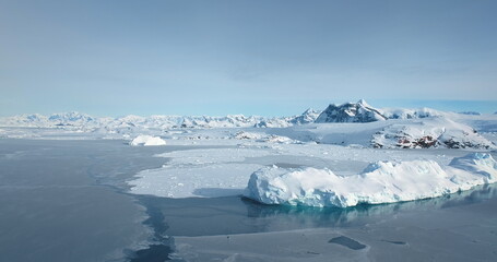 Amazing winter wild nature landscape in Antarctica. Snow covered icebergs and mountain range under blue sky. Frozen polar ocean surface background. Antarctic travel, exploration. Discover South Pole