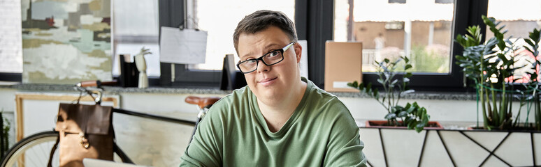 Young man with Down syndrome smiles at camera in room with bicycle and plants