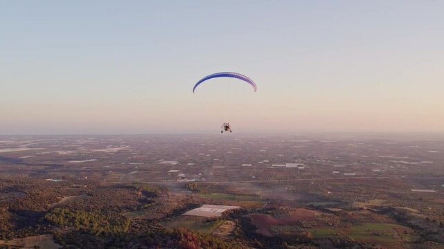 Aerial view of Paramotor flying at sunset over Ginosa, Taranto, Italy.