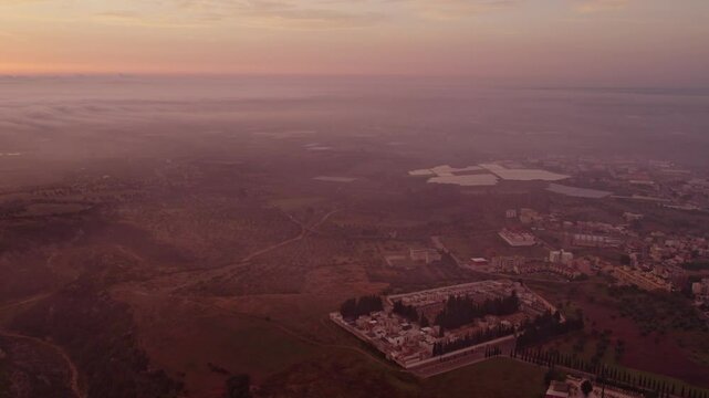 Aerial view of foggy sunrise over cityscape and fields, Ginosa, Italy.