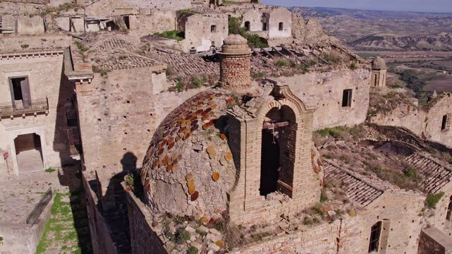 Aerial view of abandoned medieval town with church and brick buildings, Craco, Italy.