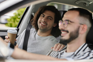 A loving gay couple enjoys a car ride together.