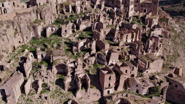 Aerial view of abandoned town with ruins and church on hill, Craco, Matera, Italy.