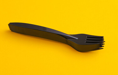 Black plastic forks on a yellow background