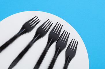 Black plastic forks on blue white background