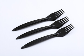 Black plastic forks on a white background