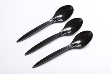 Black plastic spoons on blue white background