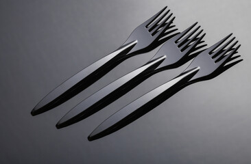 Black plastic forks on a dark background