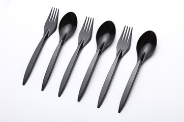 Black plastic spoons and forks on white background