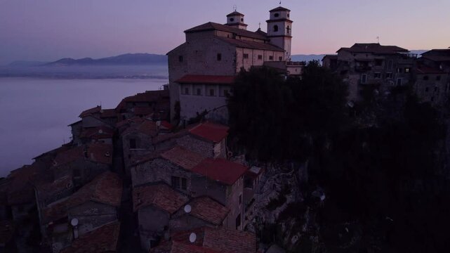 Aerial view of Santo Stefano church in sunrise with fog and clouds, Artena, Italy.
