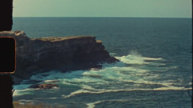 Super 8 film vintage of waves breaking splashing on rocky headland ocean sea coastline in Maroubra beach Sydney cliff face nature travel tourism light leaks
