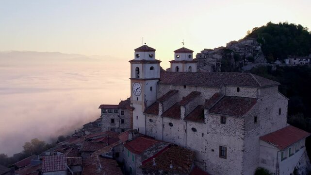 Aerial view of Santo Stefano church in sunrise with fog and mountain, Artena, Italy.