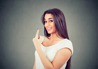 Smiling cunning woman giving number one hand gesture 