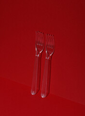 Plastic transparent forks on a red background
