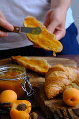 the girl spreads a croissant with jam