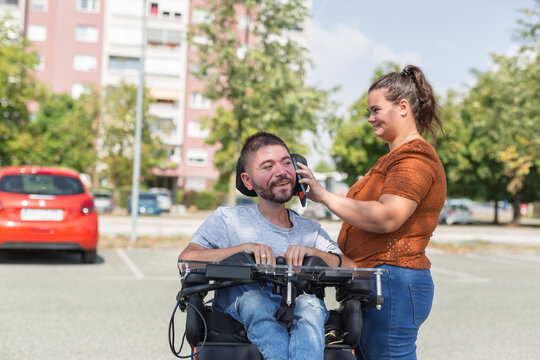 Female assistant helping a man in a wheelchair to use a smartphone. Disability and daily activity concepts.