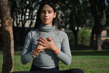 close-up of grateful woman in park with her hands on her chest and eyes closed