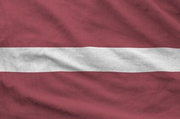 Latvia flag depicted on folded wavy fabric of old cloth close up