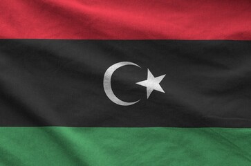 Libya flag depicted on folded wavy fabric of old cloth close up