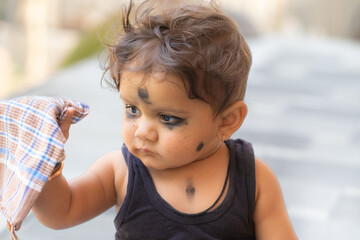 indian Child with smudged face holding plaid cloth