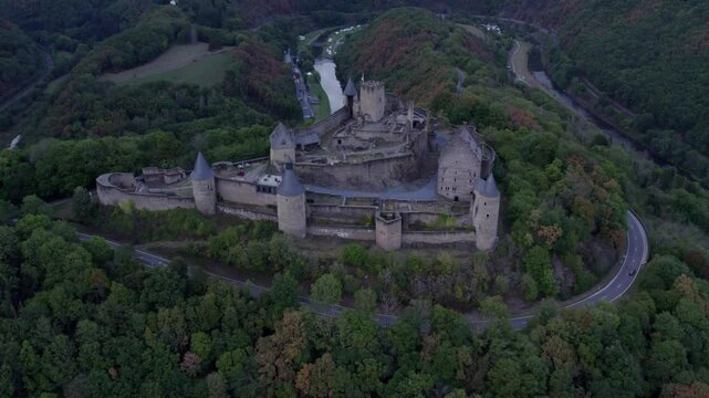 Aerial view of medieval castle surrounded by autumn trees and hills, Bourscheid, Luxembourg.