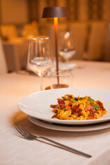 Piatto di Pasta con crema di pomodoro, basilico fresco e pancetta croccante servito in un ristorante elegante