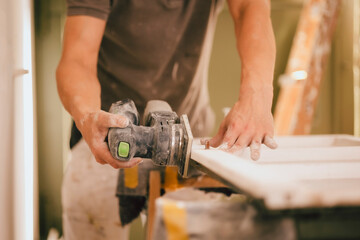 Maler setzt Schleifgerät am Fenster ein