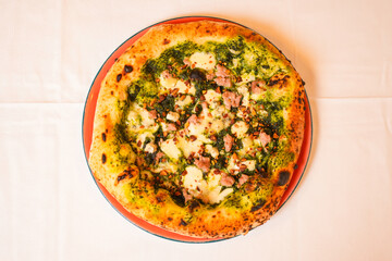 Pizza tradizionale napoletana con friarielli freschi, crema di friarielli, salsiccia e mozzarella servita in una pizzeria 