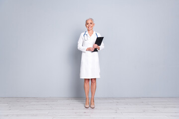 Full size photo of retired female clinic professional doctor hold paperholder wear white robe uniform isolated on gray color background