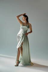 Fototapeta premium A stunning young woman with red lips poses gracefully in a dress and gloves in a studio setting, exuding an ethereal beauty.