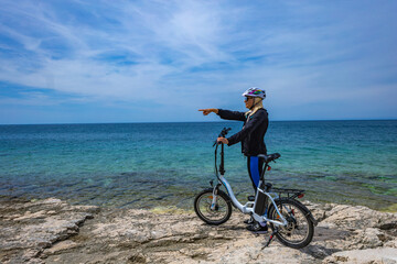 Discharged battery in an electric bike, a woman in a helmet is looking for an electric bike charger 