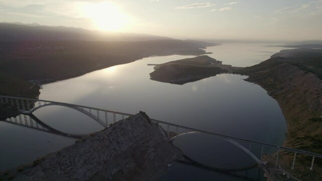 Aerial view of serene sunrise over bridge and island along the coast, Krk, Primorje-Gorski Kotar, Croatia.
